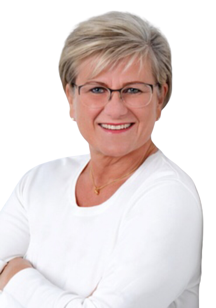 Professionelles Porträtfoto von Christiane Arndt-Schweidler, der Inhaberin von VisuBrand. Sie ist eine freundlich lächelnde Frau mittleren Alters mit kurzen, blonden Haaren und blauen Augen, die den Betrachter direkt ansieht. Sie trägt eine moderne Brille mit dunklem Rahmen, ein schlichtes weißes Langarmshirt und eine feine goldene Halskette. Ihre Arme sind selbstbewusst vor dem Körper verschränkt. Der Hintergrund ist transparent, was das Bild für die Platzierung auf verschiedenen Designs vorbereitet.